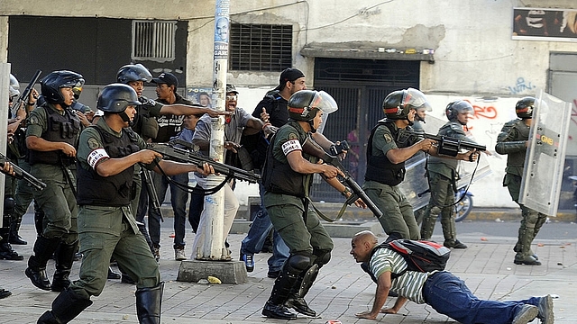 

A demonstrator lies on the ground while National Guard prepare to shoot during an opposition demontration against the government of Venezuelan President Nicolas Maduro, in Caracas on February 12, 2014. Unidentified assailants on a motorcycle fired into a crowd of anti-government protesters, leaving at least two people wounded and a pro-government man dead. AFP PHOTO / LEO RAMIREZ (Photo credit should read LEO RAMIREZ/AFP/Getty Images)