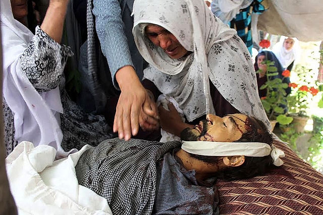 <b>An Afghan relative mourns alongside the body of a victim
killed in a terror attack. Photo credit: SHARIF SHAYEQ/AFP/GettyImages</b>