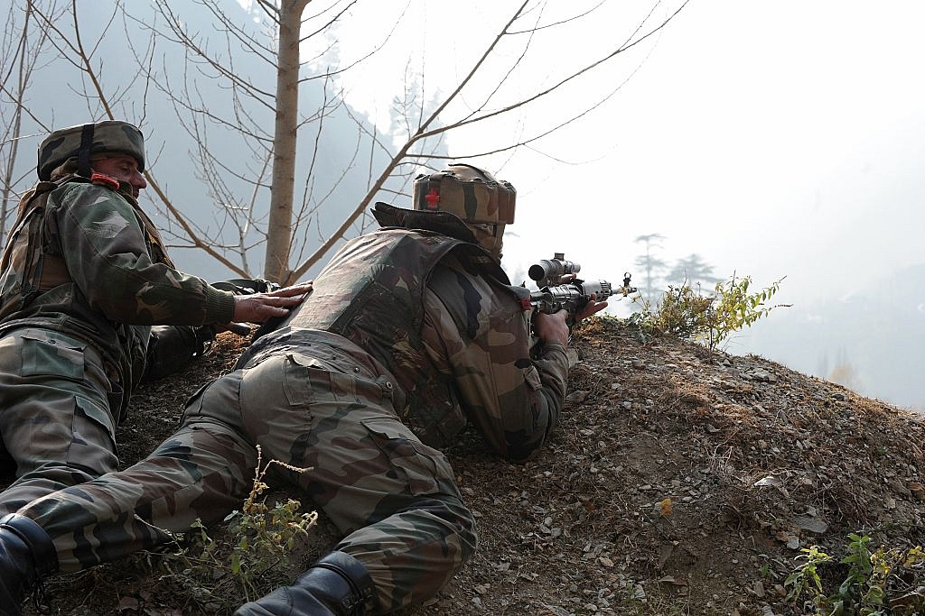 
Indian soldiers look on from their position by a road overlooking army barracks.  (ROUF BHAT/AFP/GettyImages)