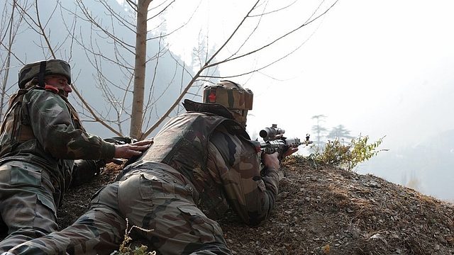 
Indian soldiers look on from their position by a road overlooking army barracks.&nbsp; (Photo credit should read ROUF BHAT/AFP/Getty Images)

