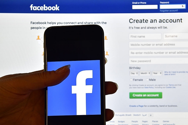 The Facebook app logo in front of a computer screen showing the Facebook login page (Photo credits: Carl Court/GettyImages)