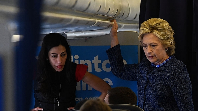 US Democratic presidential nominee Hillary Clinton talks to staff as aide Huma Abedin (L) listens onboard their campaign plane (JEWEL SAMAD/AFP/Getty Images)