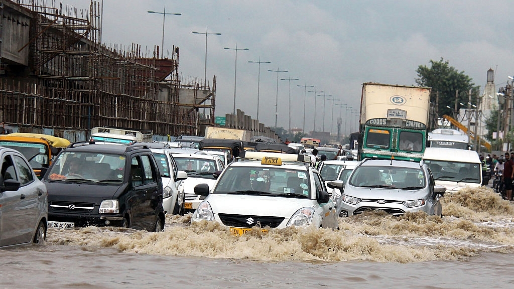 Indian commuters struggle through floodwaters beside a
partially constructed highway in Gurgaon south of New Delhi. Photo credit: STR/AFP/GettyImages &nbsp; &nbsp; &nbsp;
