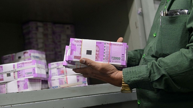 An Indian bank employee checks stacks of new Rs 2,000 notes. (SAM PANTHAKY/AFP/Getty Images)