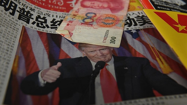 A Chinese newspaper featuring a photo of US President-elect Donald Trump that reads ‘President Trump shakes America’, is partially covered by a 100 Yuan note on a news stand. (GREG BAKER/AFP/Getty Images)