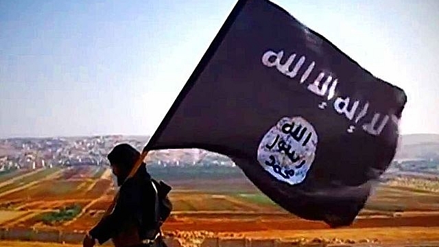 Islamic State fighter carrying their flag (Wikimedia Commons)