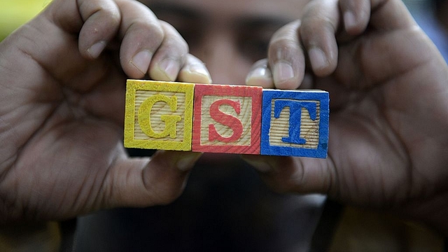 An Indian consumer goods trader shows letters GST representing goods and services tax. (NOAH SEELAM/AFP/GettyImages)