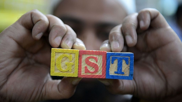 An Indian consumer goods trader shows letters GST representing ‘goods and services tax’. (NOAH SEELAM/AFP/Getty Images)