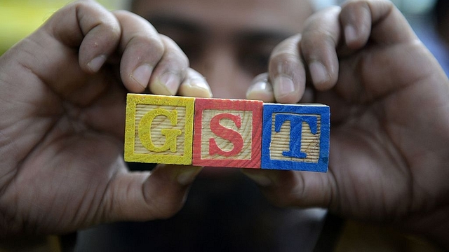  Man holds cubes with GST written on them. (NOAH SEELAM/AFP/Getty Images)