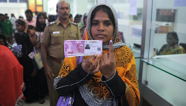 

A Indian woman poses with new 2000 rupee notes. (ARUN SANKAR/AFP/Getty Images)