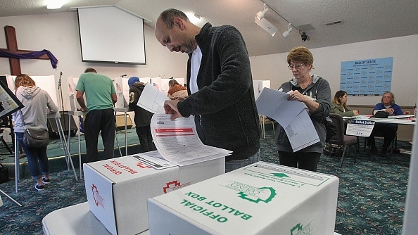 A voter prepares to place his ballot in a ballot box at a polling station in Big Bear, California: Photo credit: BILL WECHTER/AFP/GettyImages