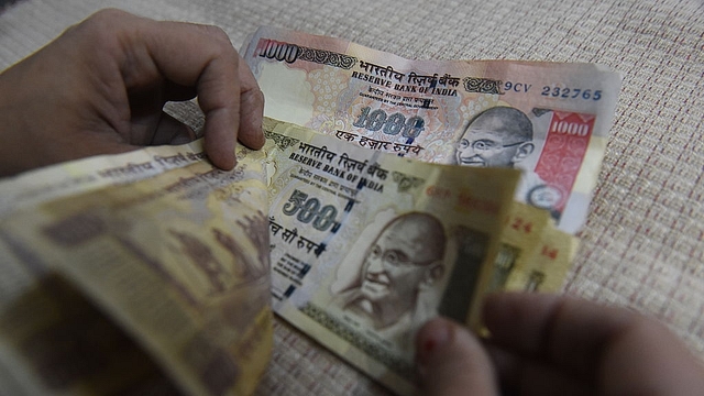 An Indian resident counts old Rs 500 and Rs 1,000 currency notes at her home. Photo credit: PRAKASH SINGH/AFP/Getty Images