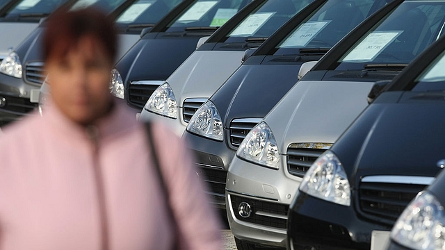 A woman walks past cars parked in a dealership. (Sean Gallup/GettyImages)