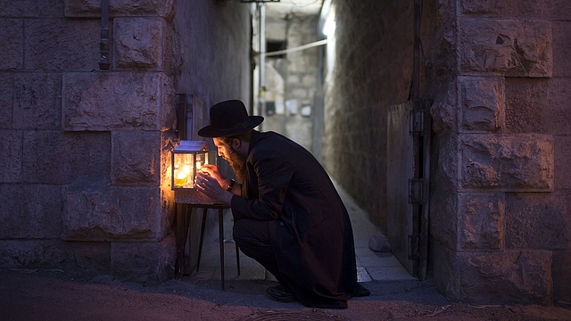 An Ultra-Orthodox Jewish man prays and lights candles on the fifth night of the Jewish holiday of Hanukkah, the festival of light, in Jerusalem, Israel. (Uriel Sinai/Getty Images)