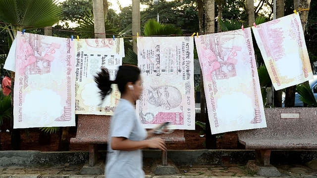 

A jogger passes replica prints of the demonetised 500 and 1000 rupee notes as part of a street art exhibition in Mumbai on November 20, 2016 (INDRANIL MUKHERJEE/AFP/Getty Images)