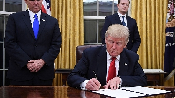 

US President Donald Trump signs an executive order as Vice President Mike Pence looks on at the White House in Washington, DC. (JIM WATSON/AFP/Getty Images)