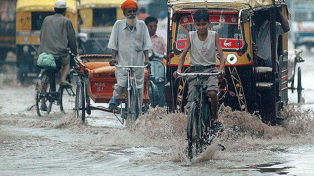 Indian commuters make their way along a waterlogged street during a heavy downpour of monsoon rain in Amritsar. (NARINDER NANU/AFP/Getty Images)