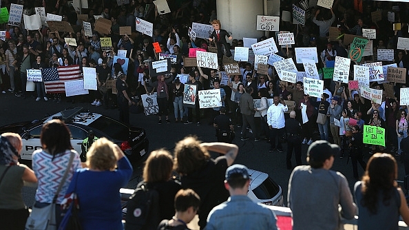 Protesters hold signs during a demonstration against the immigration ban that was imposed by US President Donald Trump at Los Angeles International Airport on 29 January 2017 in Los Angeles, California. (Justin Sullivan/Getty Images)