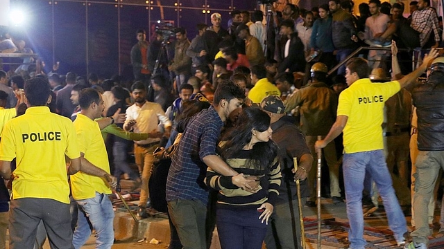 An Indian man helps a woman leave as police personnel try to manage crowds during New Year’s Eve celebrations in Bengaluru. (STR/AFP/Getty Images)