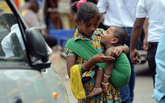 

A girl carrying a toddler counts money collected by begging from commuters in Mumbai. (INDRANIL MUKHERJEE/AFP/GettyImages)