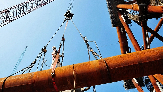 A worker stands on pipes at an offshore oil engineering company in Qingdao, in China’s eastern Shandong province. (STR/AFP/Getty Images)