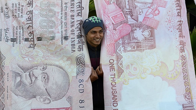 A man poses with replica prints of the demonetised Rs 500 and Rs 1,000 notes as part of a street art exhibition in Mumbai. (INDRANIL MUKHERJEE/AFP/Getty Images) 