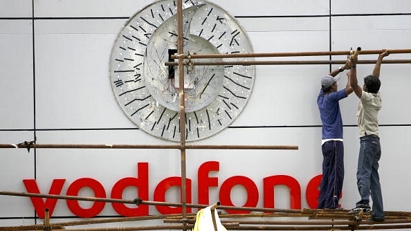 Workers put up the signboard of Vodafone at their corporate office in Mumbai. (SAJJAD HUSSAIN/AFP/GettyImages) <br>