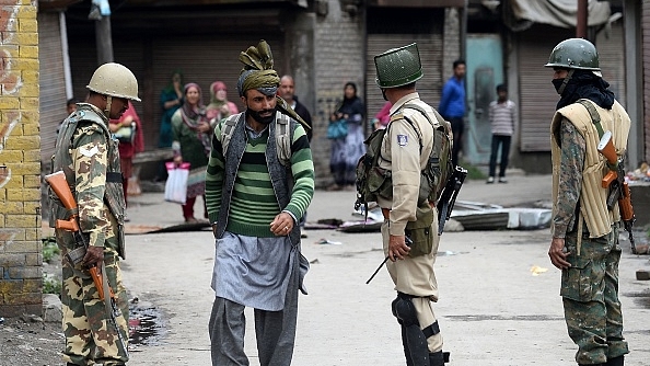 Indian troopers look on as a Kashmiri pedestrian walks along a street in Srinagar. (SAJJAD HUSSAIN/AFP/Gettymages)