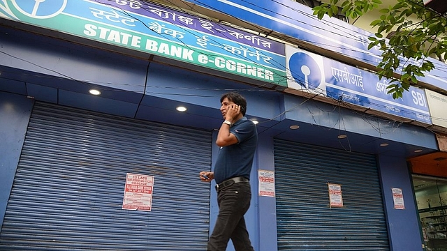 

A man speaks on his cellphone as he walks past a State Bank of India branch in Siliguri. (DIPTENDU DUTTA/AFP/GettyImages)