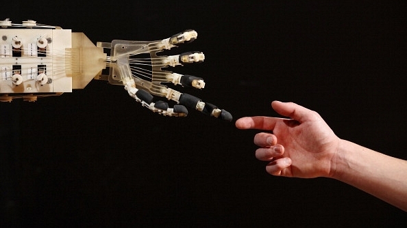 Robotics student Gildo Andreoni interacts with a Dexmart robotic hand built at the University of Bologna in the Robotville exhibition in London, England. (Oli Scarff/Getty Images)