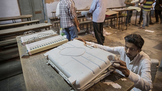 An election worker closes up an EVM before sealing it after the final polls closed in Varanasi, India. (Kevin Frayer/GettyImages)