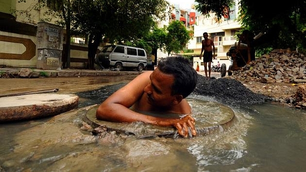 A person engaging in manual scavenging work without protective gear (Dalit Network/Wikimedia Commons)