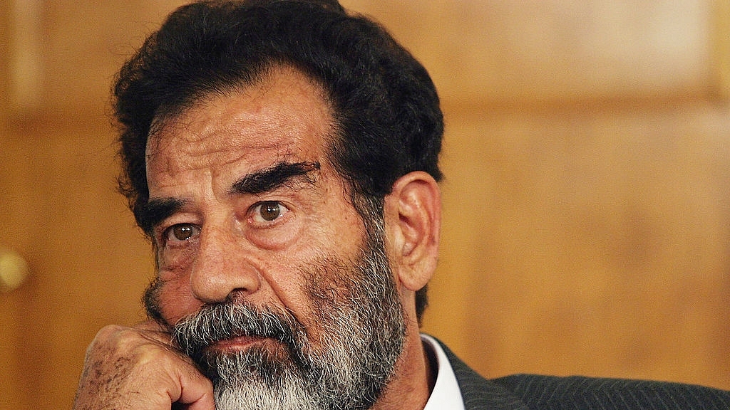 Saddam Hussein listens as a list of charges that he  will face is read in an Iraqi courtroom July 1, 2004 in Baghdad, Iraq. (Photo by Pool-Getty Images)