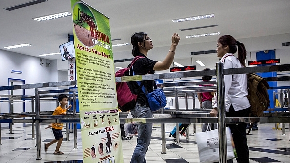 Ferry passengers arriving from Singapore walk near a banner about Zika virus at the International Ferry Terminal Batam Centre in Indonesia.&nbsp;