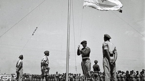 The flag of the future Jewish State is raised at morning parade at an IDF training base in 1948 in what was still the British Mandate for Palestine. (Zoltan Kluger/GPO via Getty Images)