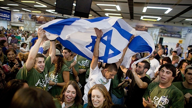 Jewish immigrants from the US wave a flag of Israel as they celebrate their arrival in the terminal hall of Ben Gurion airport near Tel Aviv, Israel. (Uriel Sinai/GettyImages)