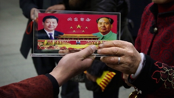 A vendor displays a souvenir with pictures of Chinese President Xi Jinping, left, and the late Mao Zedong. (Feng Li/GettyImages)