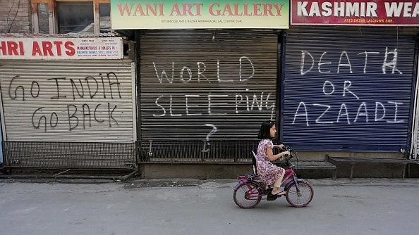 A Kashmiri girl rides bicycle in front of closed shops during restrictions in Srinagar. (Waseem Andrabi/Hindustan Times via GettyImages)