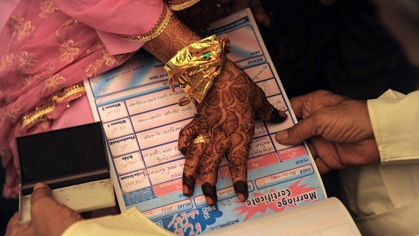 An Indian Muslim bride puts a thumb impression on a marriage certificate in the presence of religious leaders and a relative during a mass wedding ceremony in Ahmedabad. (SAM PANTHAKY/AFP/GettyImages)