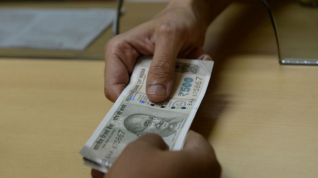 A bank staff member hands Indian 500 rupee notes to a customer on November 24, 2016, in the wake of the demonetisation of old 500 and 1000 rupee notes in Mumbai. (INDRANIL MUKHERJEE/AFP/Getty Images)