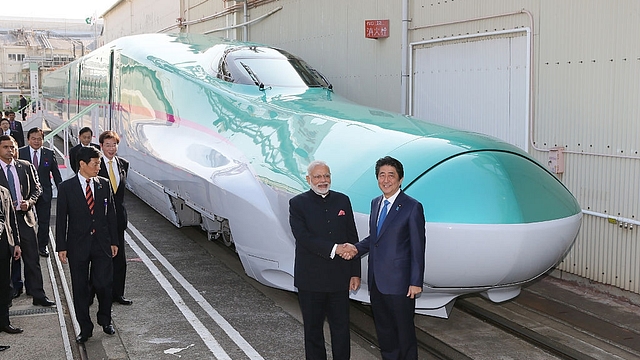 Prime Minister Narendra Modi  and his Japanese counterpart Shinzo Abe  shake hands in front of a shinkansen train during their inspection at a bullet train manufacturing plant in Kobe, Hyogo prefecture on 12 November 2016. (JIJI PRESS/AFP/Getty Images)