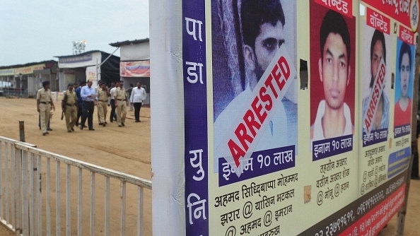 A police team walk past a poster featuring wanted and arrested alleged militants Yasin Bhatkal  and Asadullah Akhtar  during a security inspection in Mumbai. (INDRANIL MUKHERJEE/AFP/GettyImages)&nbsp;