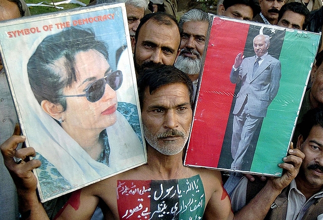An activist of the Pakistan Peoples Party holds pictures of former prime minister Benazir Bhutto and his father former prime minister Zulfiqar Ali Bhutto in Lahore during a rally. (ARIF ALI/AFP/GettyImages)