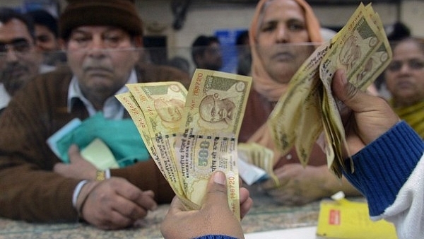 An Indian bank teller counts out notes as citizens gather inside a bank to deposit and exchange old Rs 500 and Rs 1,000 notes. (NARINDER NANU/AFP/Getty Images)