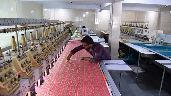 An Indian textile maker works on an embroidery machine at a workshop. (SAM PANTHAKY/AFP/Getty Images)