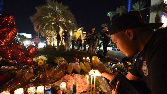 Edrian Pateno of Corona, California lights candles at a makeshift memorial near the Mandalay Hotel on the Las Vegas Strip on 3 October, after a gunman killed 59 people and wounded more than 500 others, before taking his own life, when he opened fire from a hotel on a country music festival.&nbsp; (Robyn Beck/AFP/GettyImages)