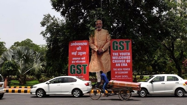 Indian motorists drive past a billboard displaying an image of Prime Minister Narendra Modi and announcing the implementation of the GST in New Delhi. (PRAKASH SINGH/AFP/Getty Images)