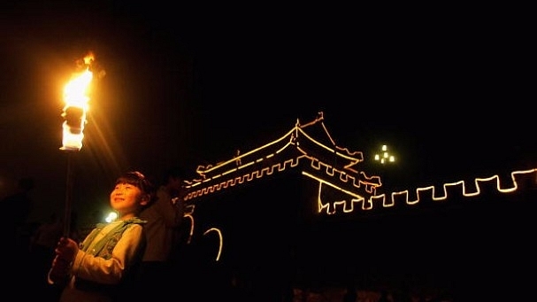  A girl holds a torch during an event to mark the Mid-Autumn Festival beside an ancient city wall in  2006 in Shouxian County of Anhui Province, China. (China Photos/Getty Images)