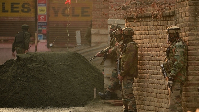 Indian army soldiers stands alert as a Kashmir boy looks on outside a house during search operations in Srinagar. (TAUSEEF MUSTAFA/AFP/Getty Images)