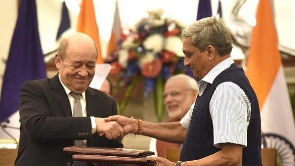 Former defence minister Manohar Parrikar and his French counterpart Jean-Yves Le Drian exchange the files of agreements on the buying of Rafale fighter jets. (Arvind Yadav/Hindustan Times via Getty Images)